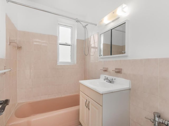 bathroom with vanity, tiled shower / bath, and tile walls