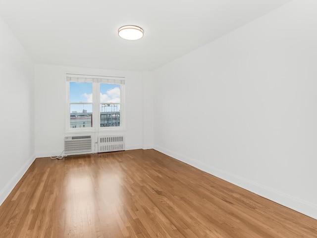 spare room with radiator heating unit, hardwood / wood-style flooring, and an AC wall unit