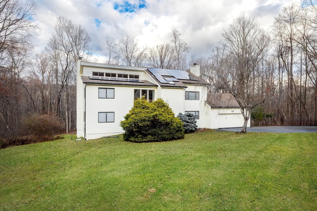 view of home's exterior with solar panels, a garage, and a lawn