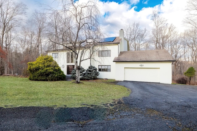 view of front of home featuring solar panels, a garage, and a front lawn