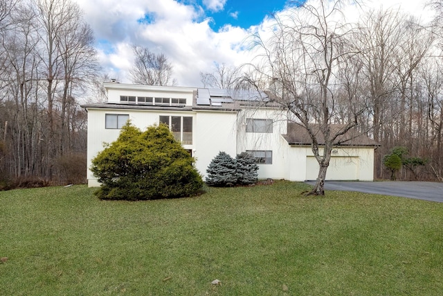 view of front of house with a front lawn, a garage, and solar panels