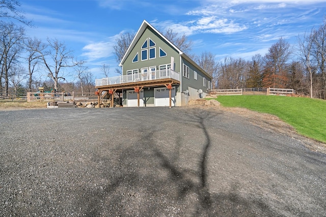 view of front of property featuring a garage, a front lawn, and a wooden deck