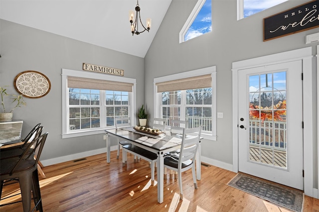 dining room featuring a chandelier, hardwood / wood-style flooring, and high vaulted ceiling