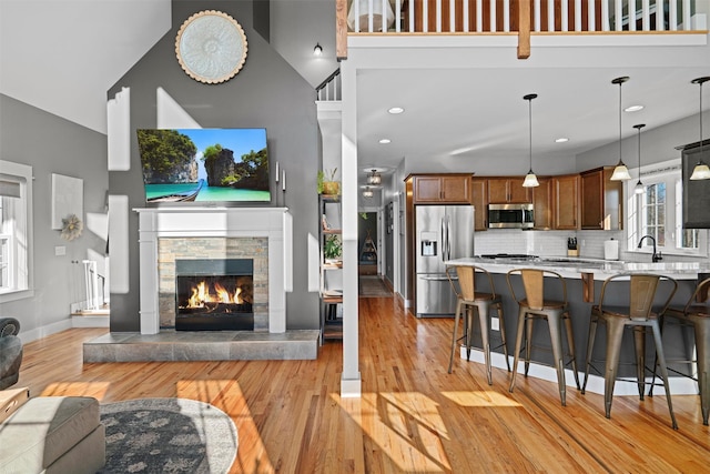 living room featuring a fireplace, a high ceiling, light hardwood / wood-style floors, and plenty of natural light