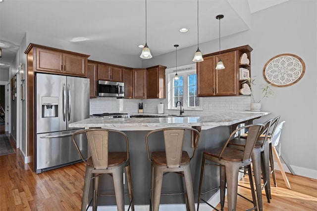 kitchen with tasteful backsplash, kitchen peninsula, pendant lighting, and appliances with stainless steel finishes