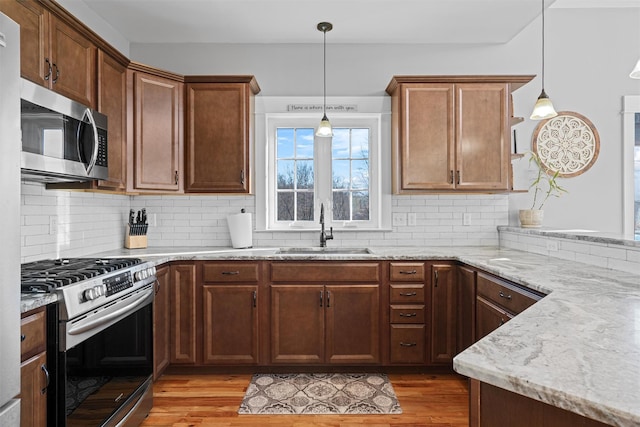 kitchen featuring backsplash, hanging light fixtures, sink, and stainless steel appliances