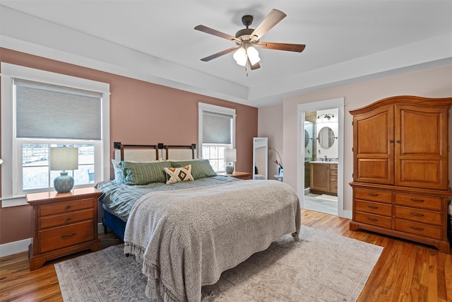 bedroom featuring ensuite bathroom, ceiling fan, and light wood-type flooring