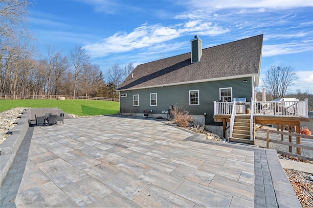 rear view of property featuring a wooden deck, a yard, and a patio