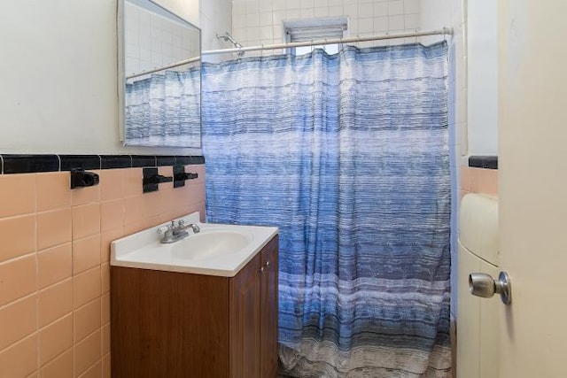 bathroom featuring vanity, curtained shower, and tile walls