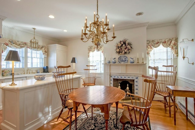 dining room featuring a baseboard heating unit, plenty of natural light, a tile fireplace, and light wood-style floors