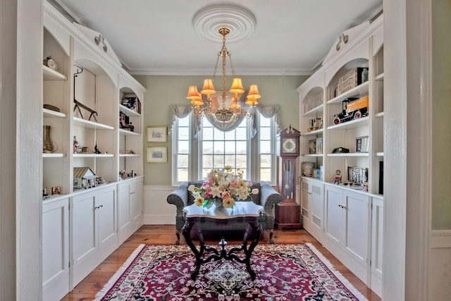 dining space with light wood-style flooring, ornamental molding, and a notable chandelier