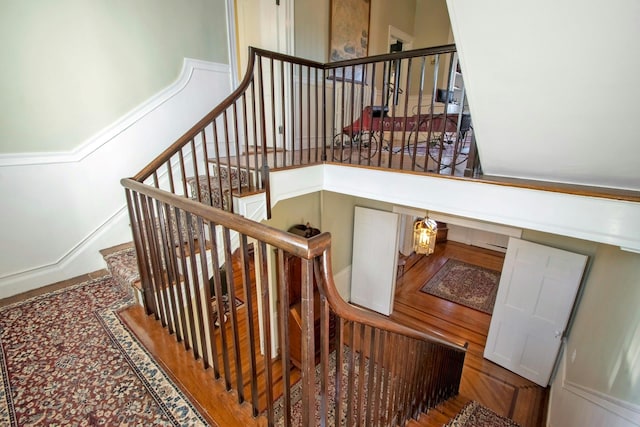 stairway featuring a high ceiling and wood finished floors