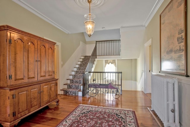 interior space featuring stairway, radiator heating unit, ornamental molding, and wood finished floors