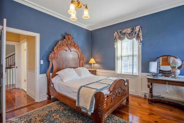 bedroom with wainscoting, crown molding, and hardwood / wood-style floors