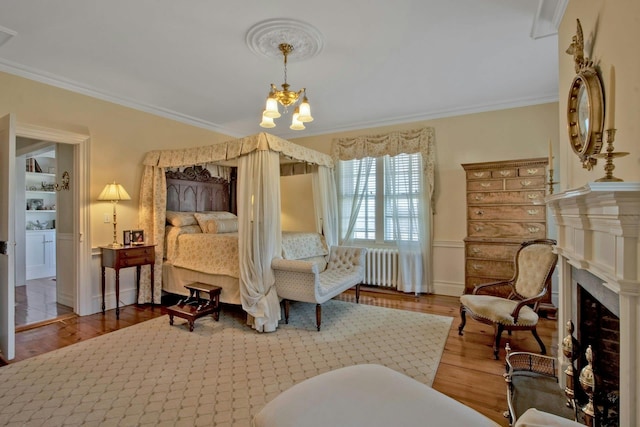 bedroom with radiator heating unit, ornamental molding, and wood finished floors