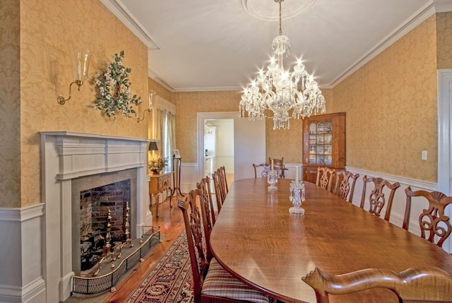 dining space with wallpapered walls, ornamental molding, a wainscoted wall, and wood finished floors