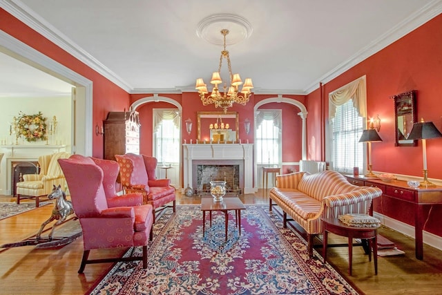 sitting room featuring crown molding, a fireplace, an inviting chandelier, wood finished floors, and baseboards