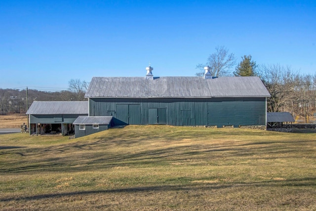 back of house featuring a barn, a lawn, and an outdoor structure