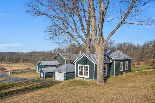 view of front facade featuring an outbuilding, metal roof, a garage, a barn, and a front lawn