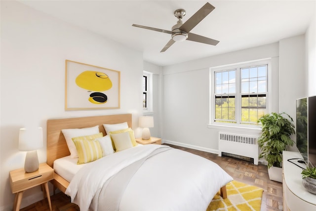 bedroom featuring parquet floors, radiator heating unit, and ceiling fan