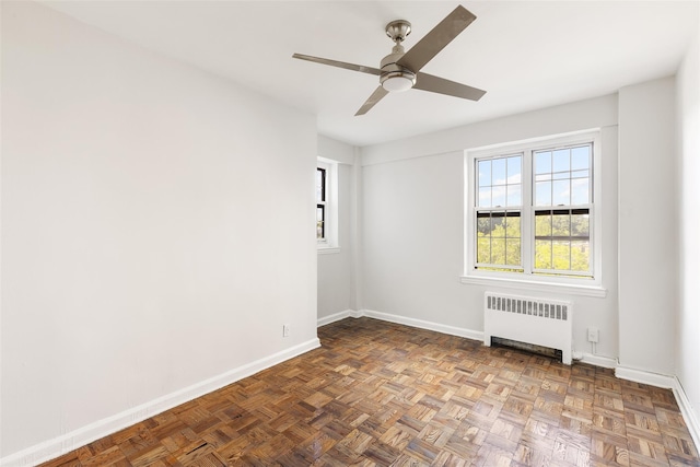 empty room featuring ceiling fan, parquet floors, and radiator