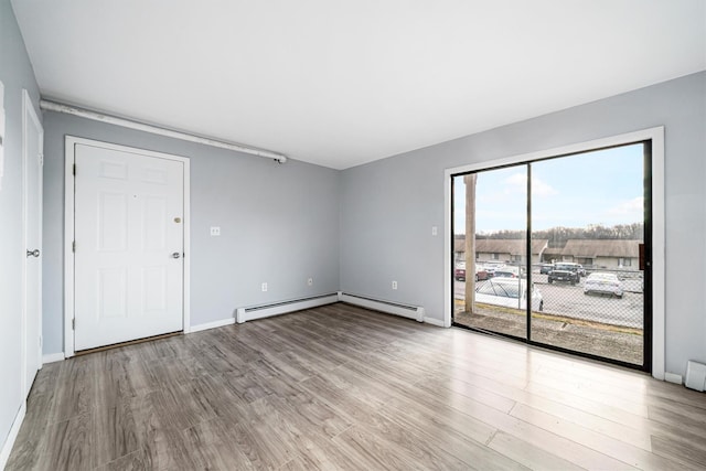 unfurnished room featuring light hardwood / wood-style floors and a baseboard heating unit