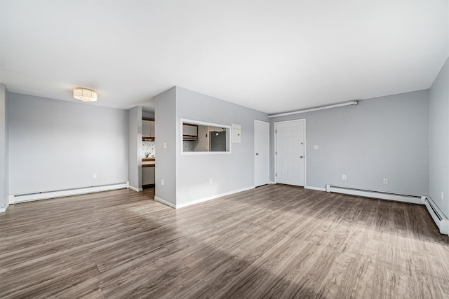 unfurnished living room featuring baseboard heating and hardwood / wood-style flooring