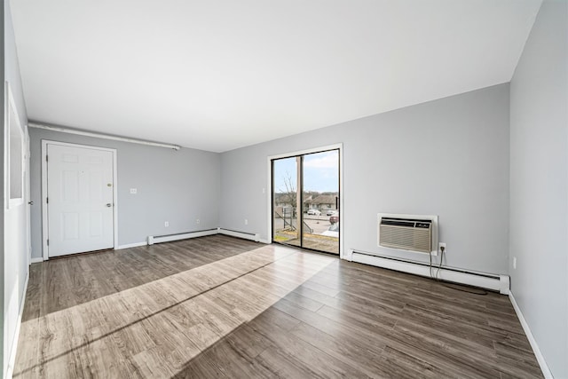 unfurnished room featuring a baseboard radiator, an AC wall unit, and hardwood / wood-style flooring