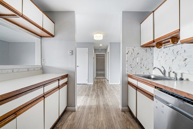 kitchen featuring white cabinetry, dishwasher, light wood-type flooring, and sink