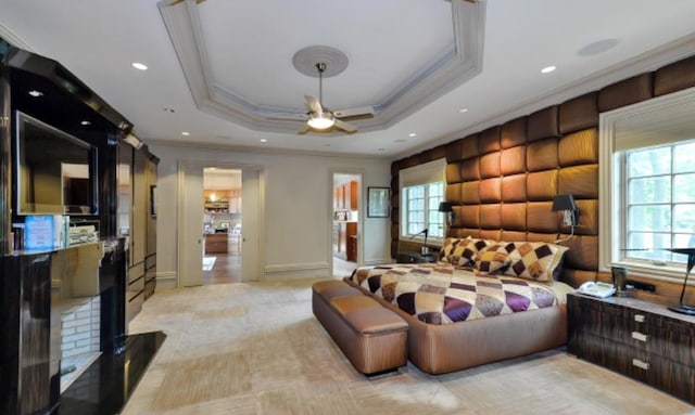 bedroom featuring a raised ceiling, multiple windows, ornamental molding, and ceiling fan