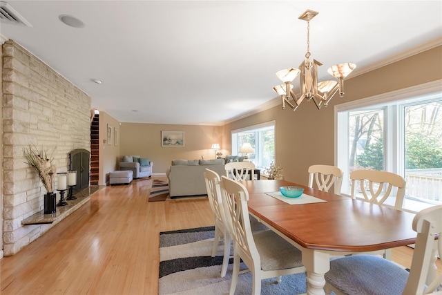 dining room with a chandelier, ornamental molding, and light hardwood / wood-style flooring