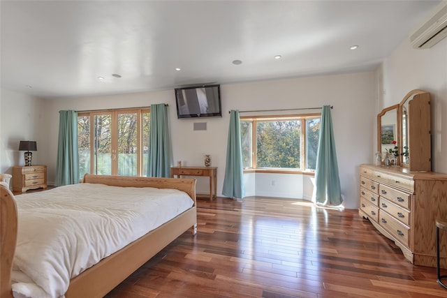 bedroom with multiple windows, dark hardwood / wood-style flooring, and a wall mounted AC