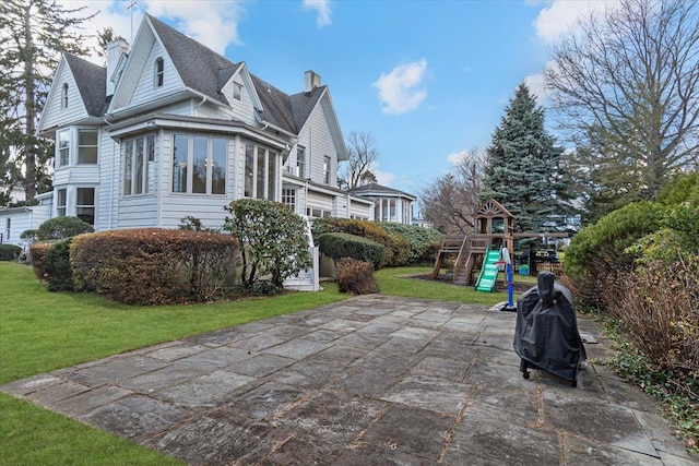 view of property exterior with a yard, a playground, and a patio area