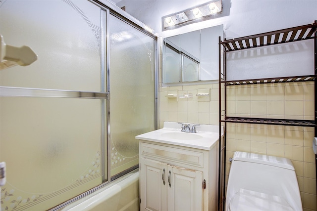 full bathroom featuring shower / bath combination with glass door, vanity, toilet, and tile walls