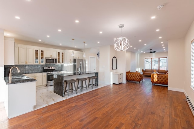 kitchen featuring stainless steel appliances, sink, pendant lighting, a center island, and light hardwood / wood-style floors