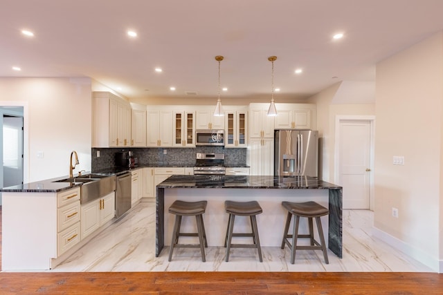 kitchen featuring a kitchen island, sink, stainless steel appliances, and hanging light fixtures