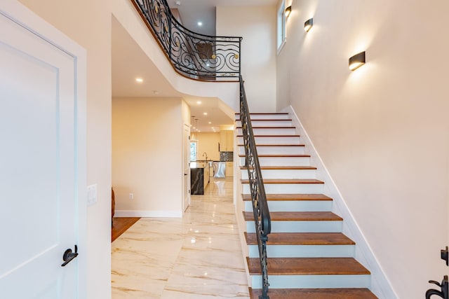 staircase featuring a high ceiling and sink