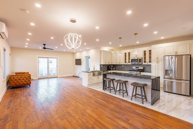 kitchen with appliances with stainless steel finishes, ceiling fan with notable chandelier, decorative light fixtures, and light hardwood / wood-style flooring