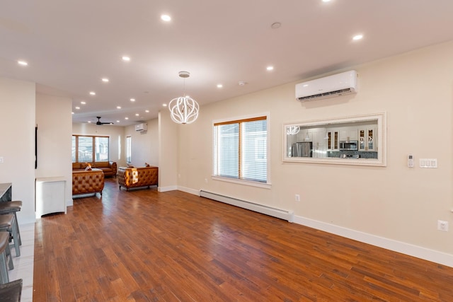 living room with a wall mounted air conditioner, hardwood / wood-style floors, ceiling fan with notable chandelier, and a baseboard heating unit