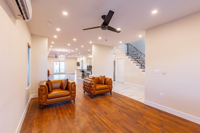 living room with wood-type flooring, a wall mounted AC, and ceiling fan