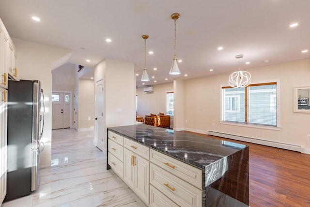 kitchen with a baseboard radiator, an AC wall unit, stainless steel fridge, dark stone counters, and pendant lighting