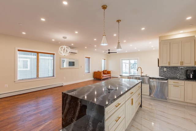 kitchen featuring hanging light fixtures, stainless steel dishwasher, ceiling fan, dark stone countertops, and a kitchen island