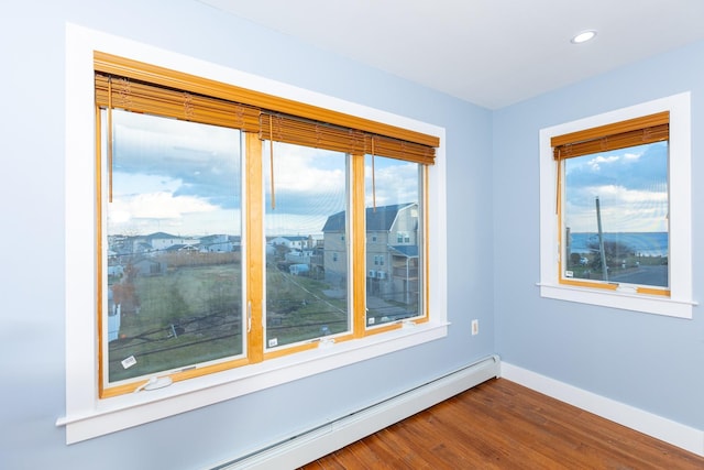 spare room featuring hardwood / wood-style floors, a baseboard radiator, and plenty of natural light