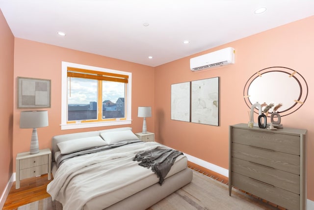 bedroom featuring light hardwood / wood-style flooring and an AC wall unit