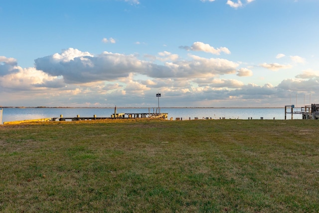 view of dock with a yard and a water view