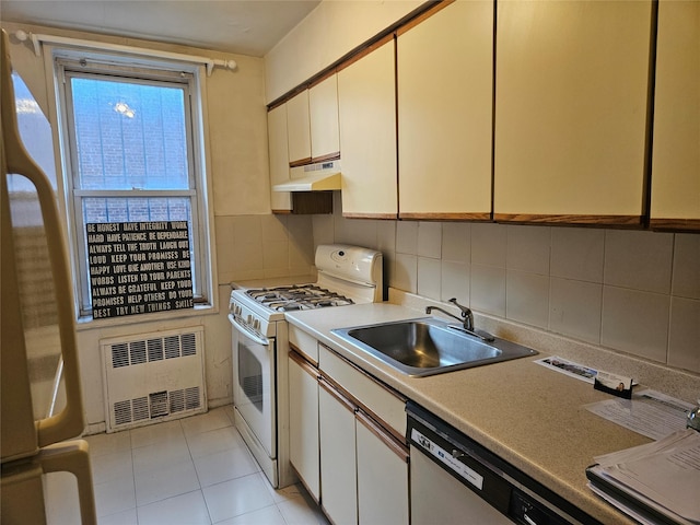 kitchen with white appliances, radiator, white cabinets, sink, and decorative backsplash