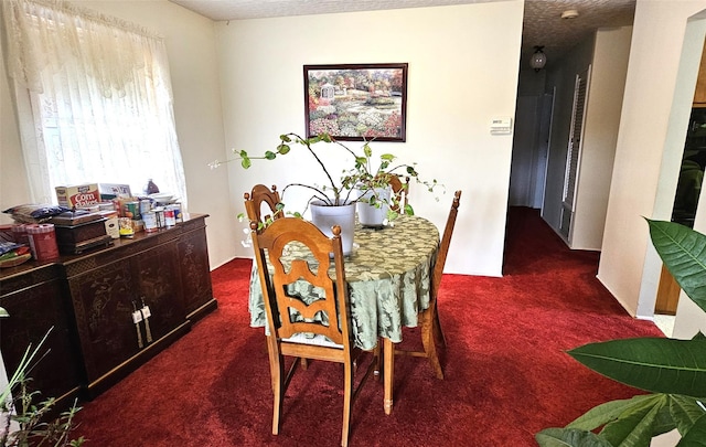 dining area with dark colored carpet and a textured ceiling