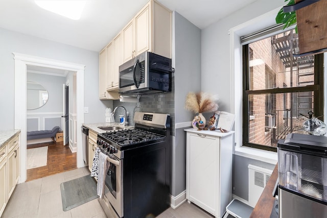 kitchen with tasteful backsplash, light stone counters, stainless steel appliances, sink, and cream cabinets