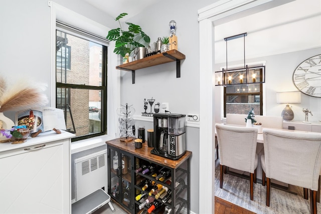 bar featuring pendant lighting, dark hardwood / wood-style flooring, radiator, and a notable chandelier