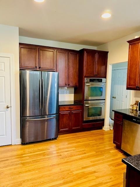 kitchen with light wood-type flooring, backsplash, and appliances with stainless steel finishes